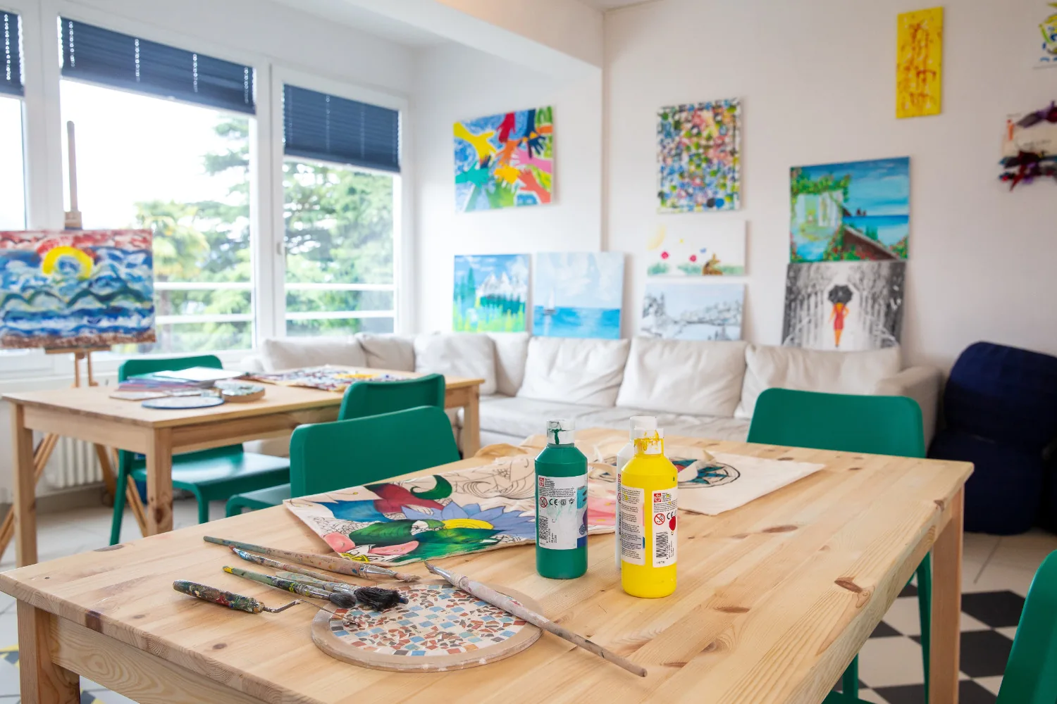 Bright sociotherapy room with a wooden table, paints and brushes and colourful paintings on the walls