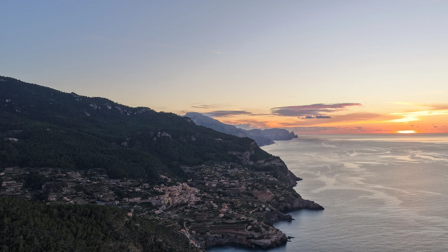 Aerial view of a steep wooded coastline and the sea at sunset on Mallorca