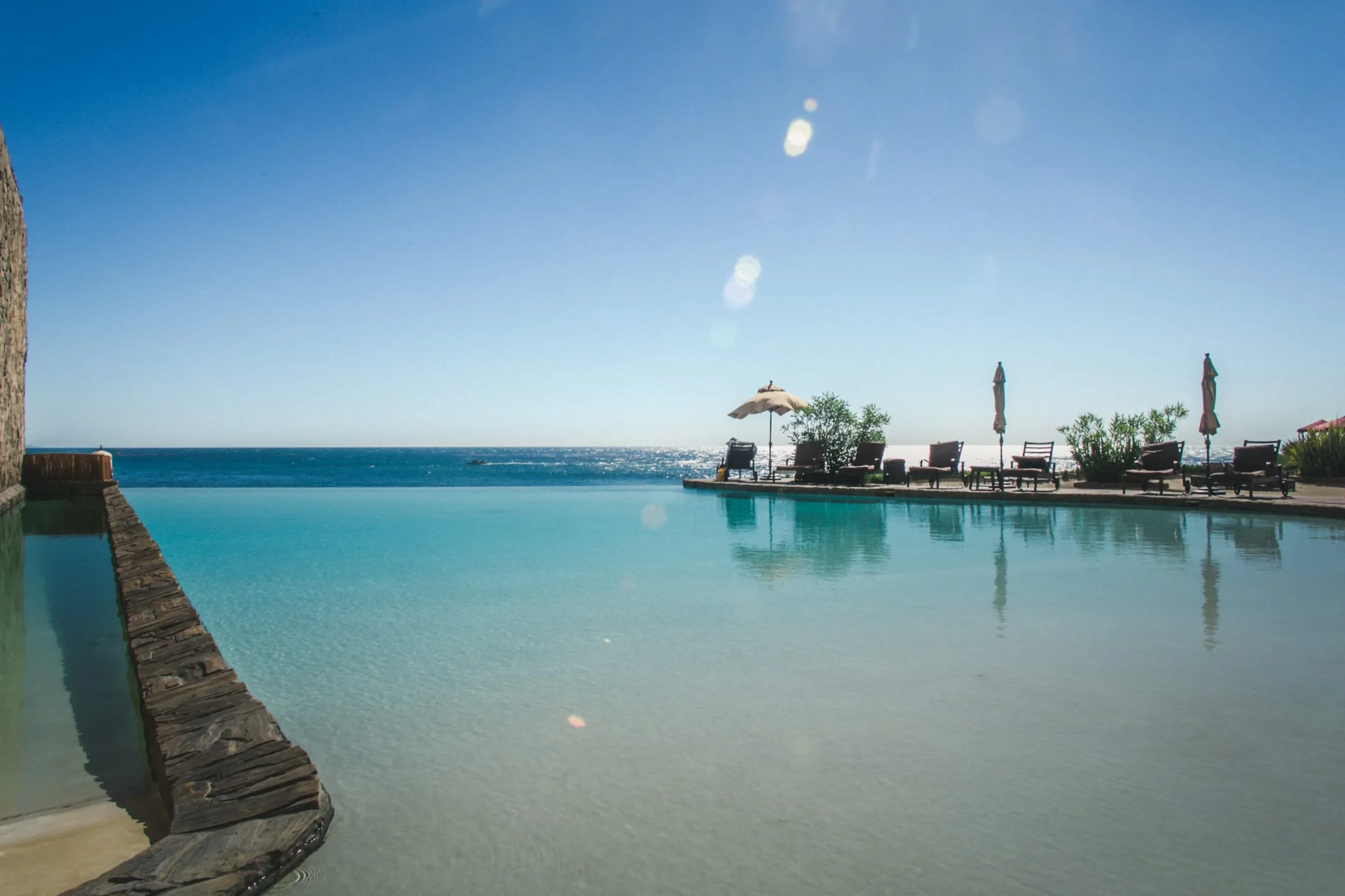Infinity pool with turquoise water merging into the Pacific Ocean under a clear blue sky