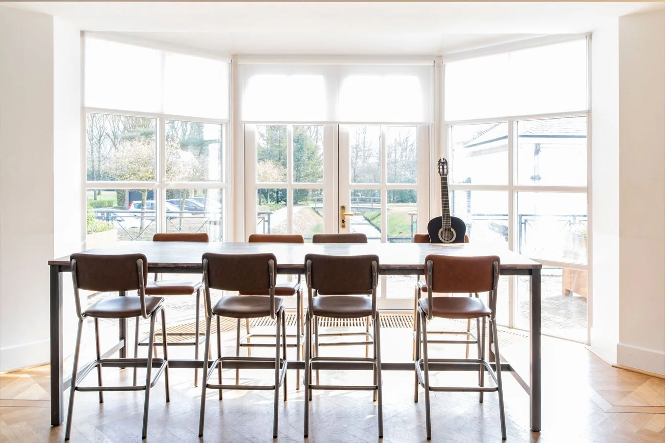 Bright room with a high table and bar stools in front of a large bay window, with a guitar by the glass