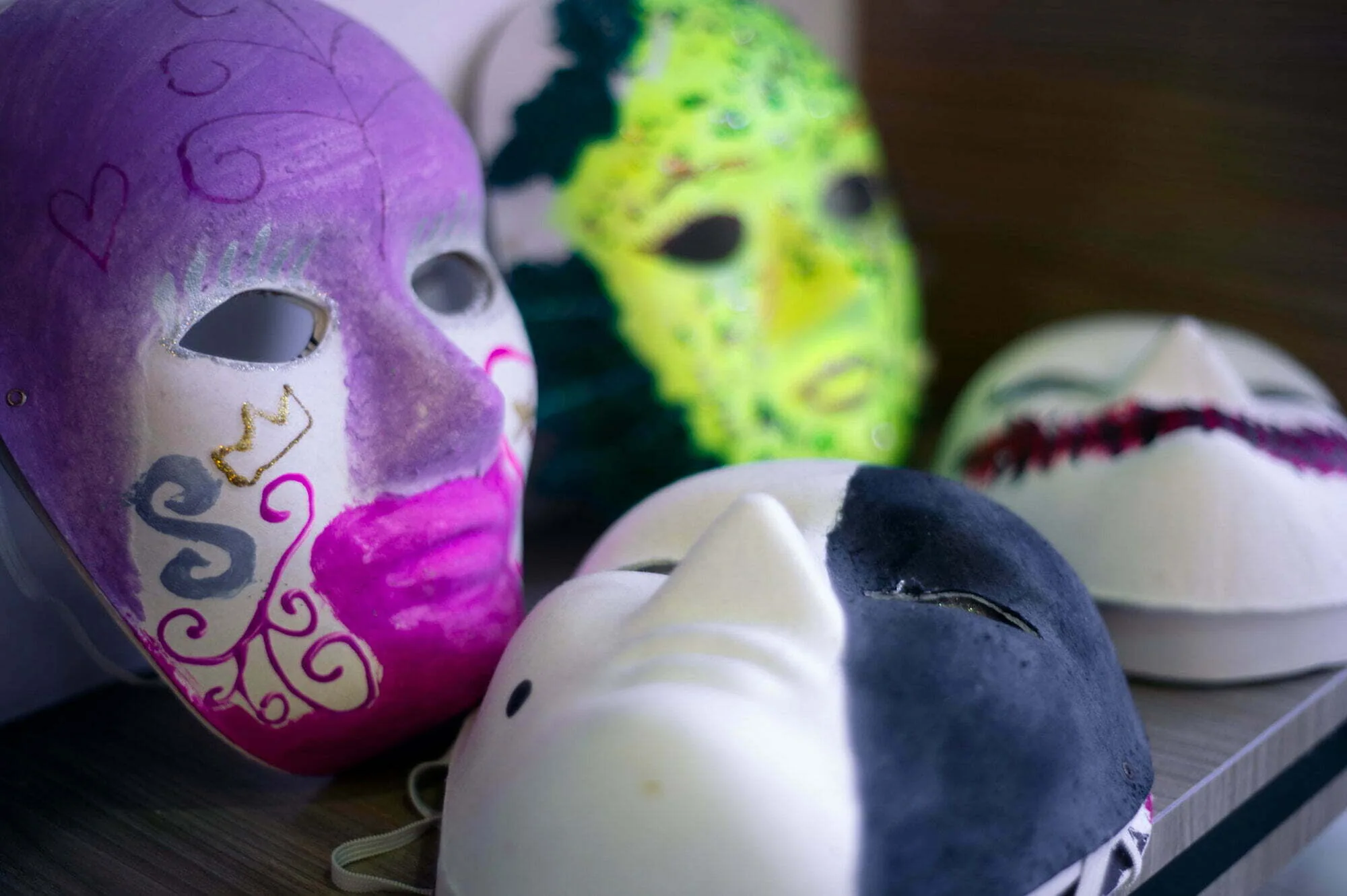 Hand painted white masks in pink, purple, yellow and black made during an art therapy session
