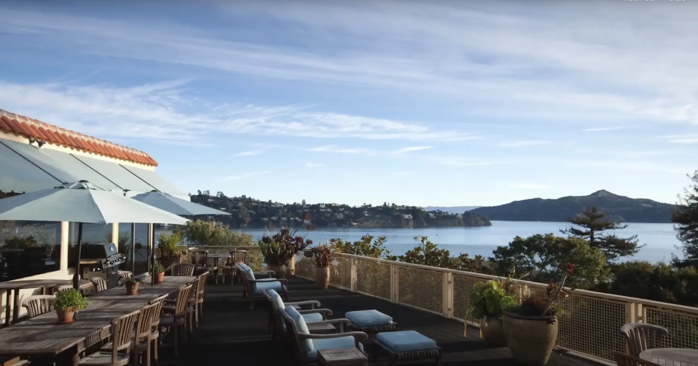 Outdoor terrace with dining tables, umbrellas and lounge chairs overlooking San Francisco Bay in Sausalito