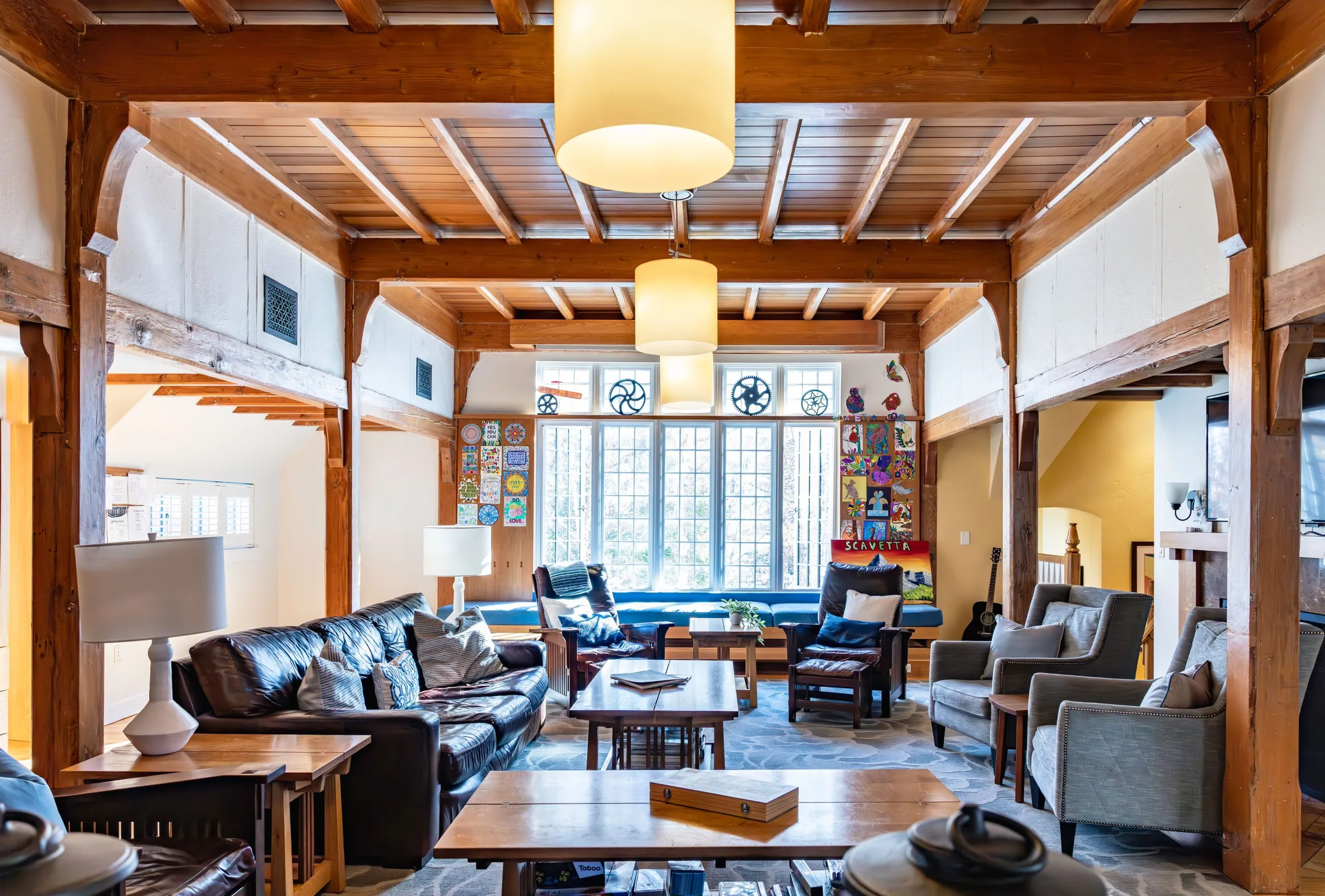Lounge in Scavetta House with exposed timber beams, leather sofas and a large paned window