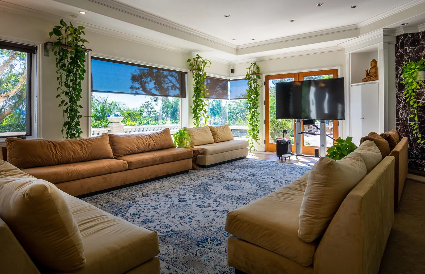 Spacious living room with brown leather sofas, a large rug, television and tall windows