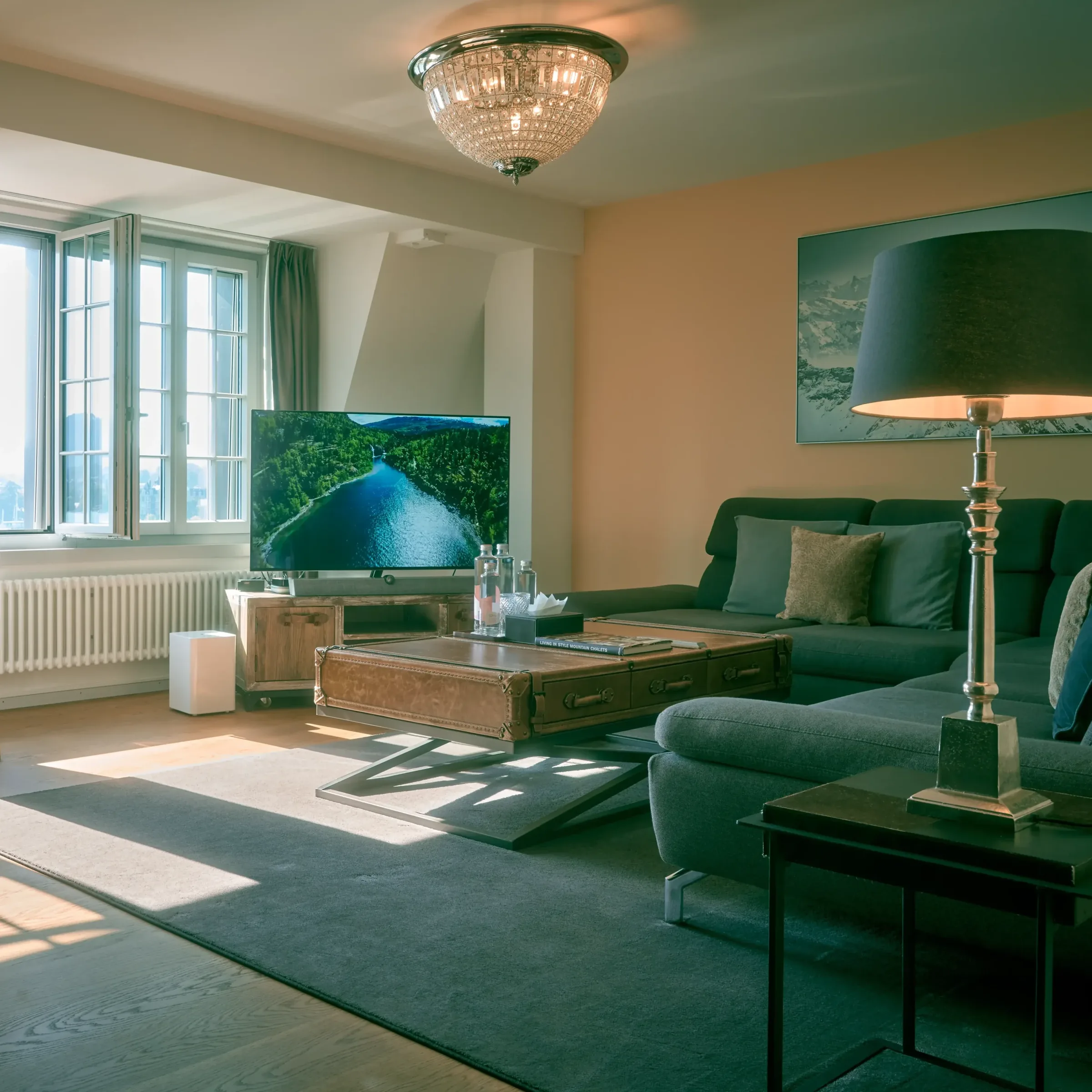 Sunlit lounge with a grey corner sofa, standing lamp, wooden coffee table and wall mounted TV