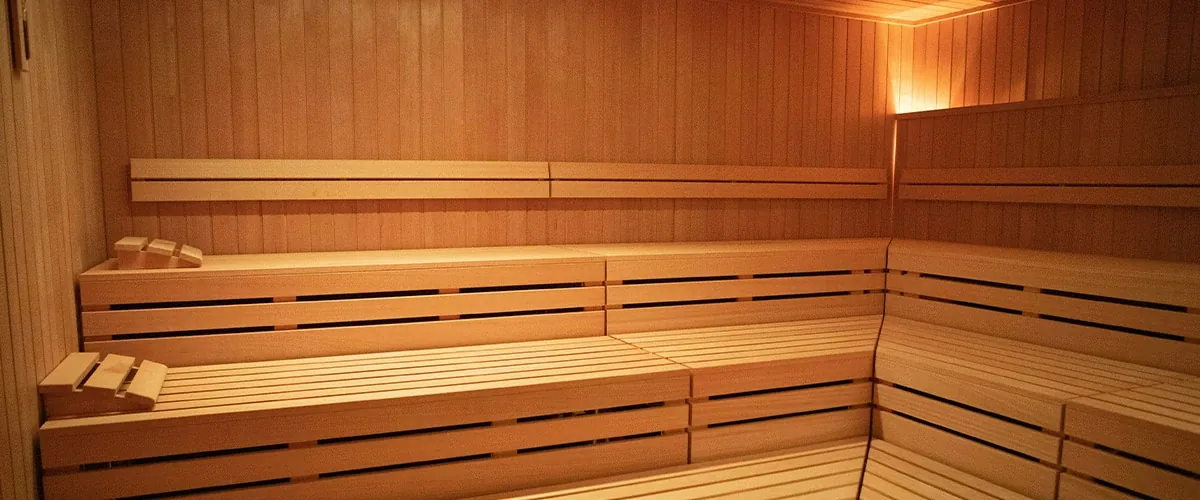 Empty wooden sauna with tiered benches and warm indirect lighting