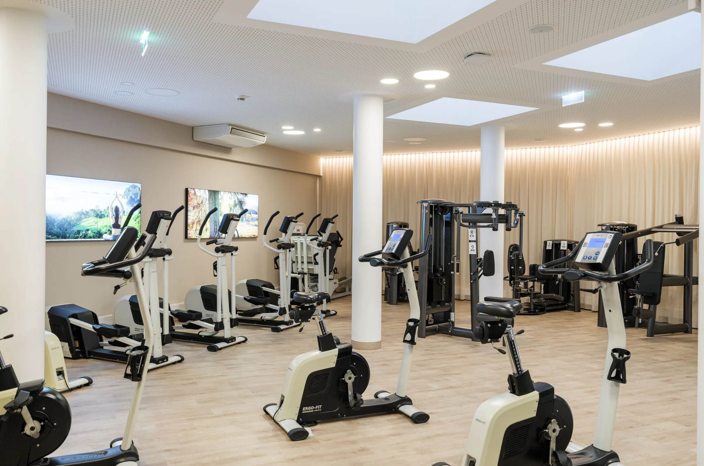 Fitness room with exercise bikes, cross trainers and weight machines under skylights