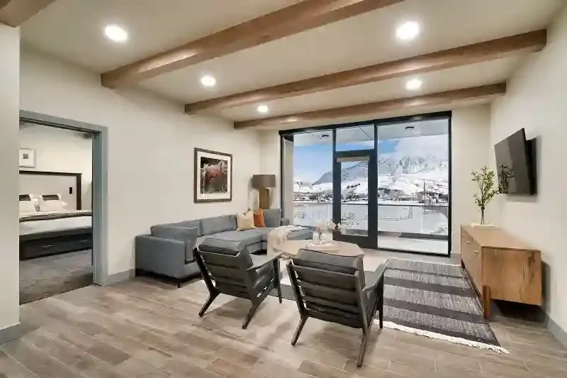 Suite living room with grey sofa, armchairs and floor to ceiling windows facing snowy mountains