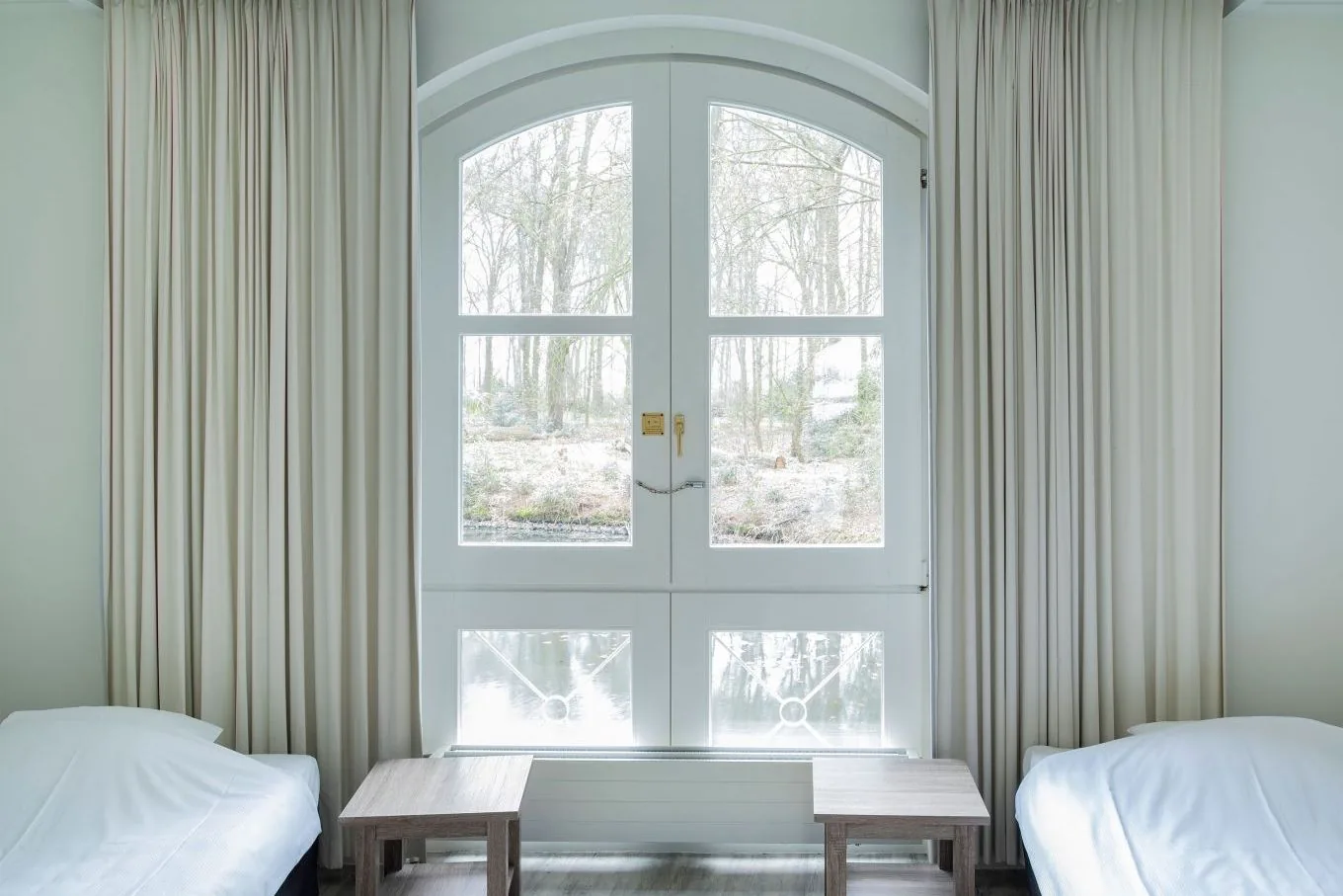 Shared bedroom with two single beds either side of arched glass doors with grey curtains