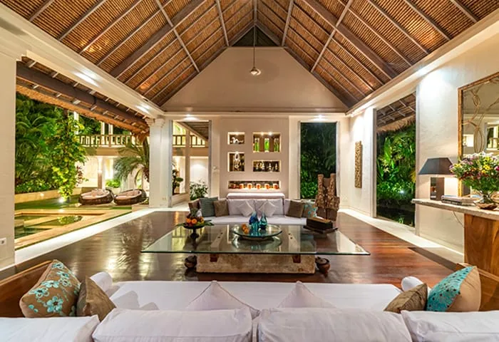 Open living pavilion with a timber vaulted ceiling, white sofas and a glass coffee table in a Bali villa