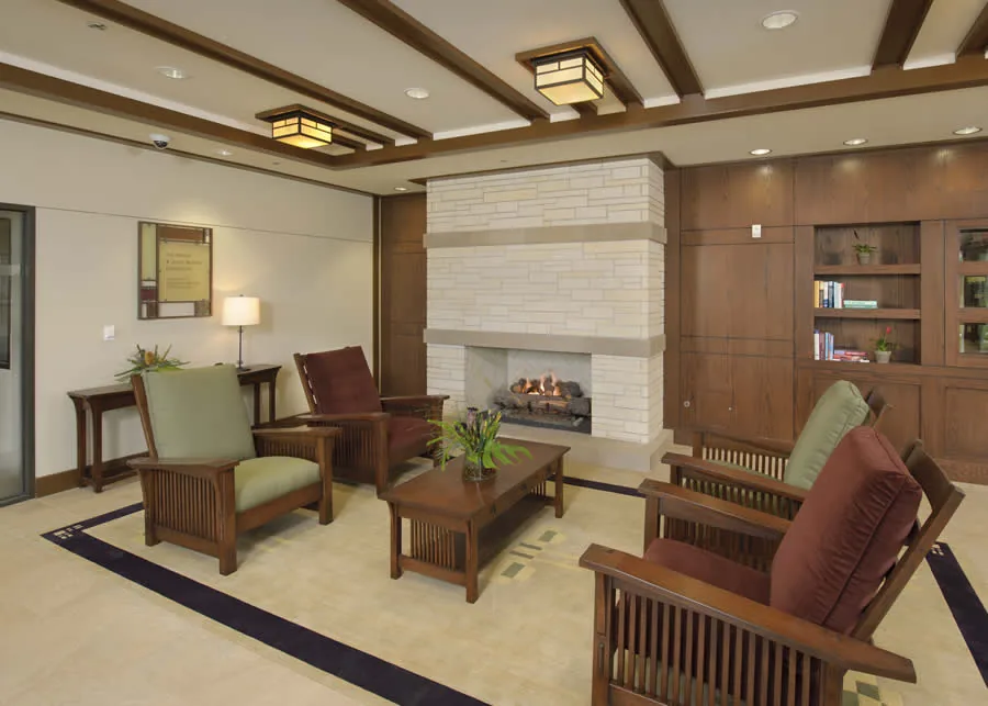 Lounge with wooden armchairs around a stone fireplace, a coffee table and built-in shelving