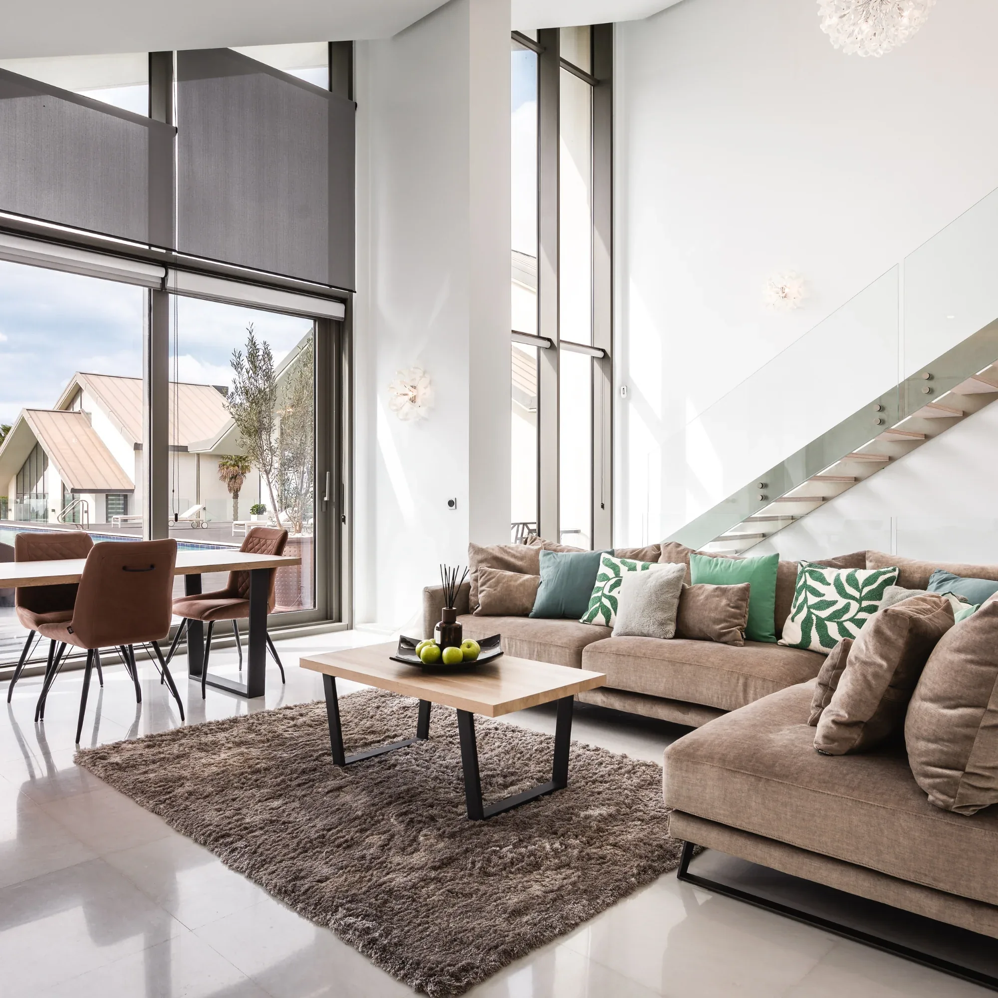 Double height living room with grey sofas, a rug, dining table and tall windows onto the garden