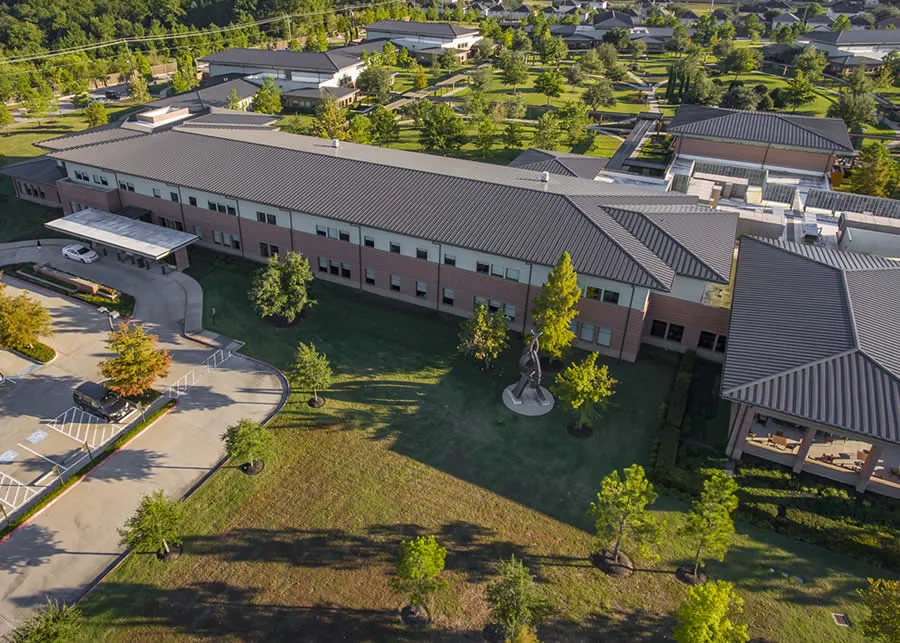 Aerial view of the Menninger Clinic campus in Houston, with long brick buildings around a tree-lined lawn