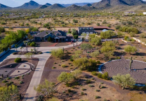 Aerial view of the estate houses, desert paths and a stone labyrinth with mountains beyond