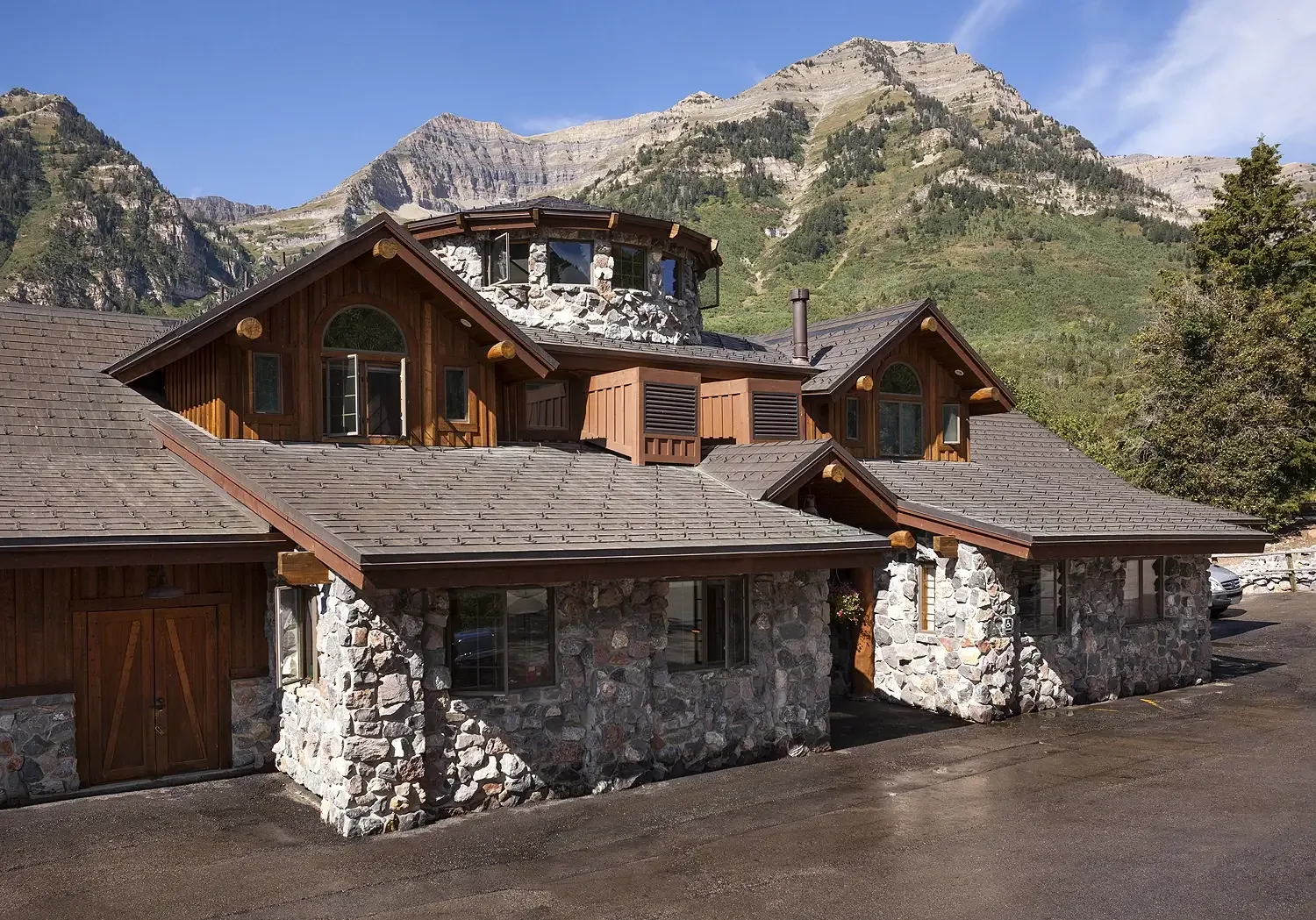 Timber and stone lodge building with a round tower below rocky mountain peaks in Sundance, Utah