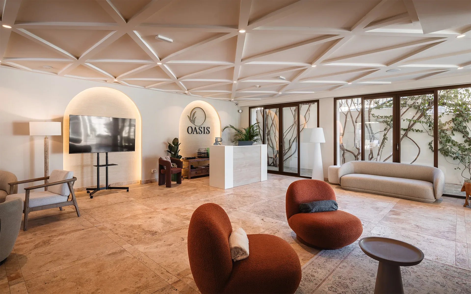 Reception lounge with rust-coloured armchairs, a white sofa, arched niche and lattice ceiling
