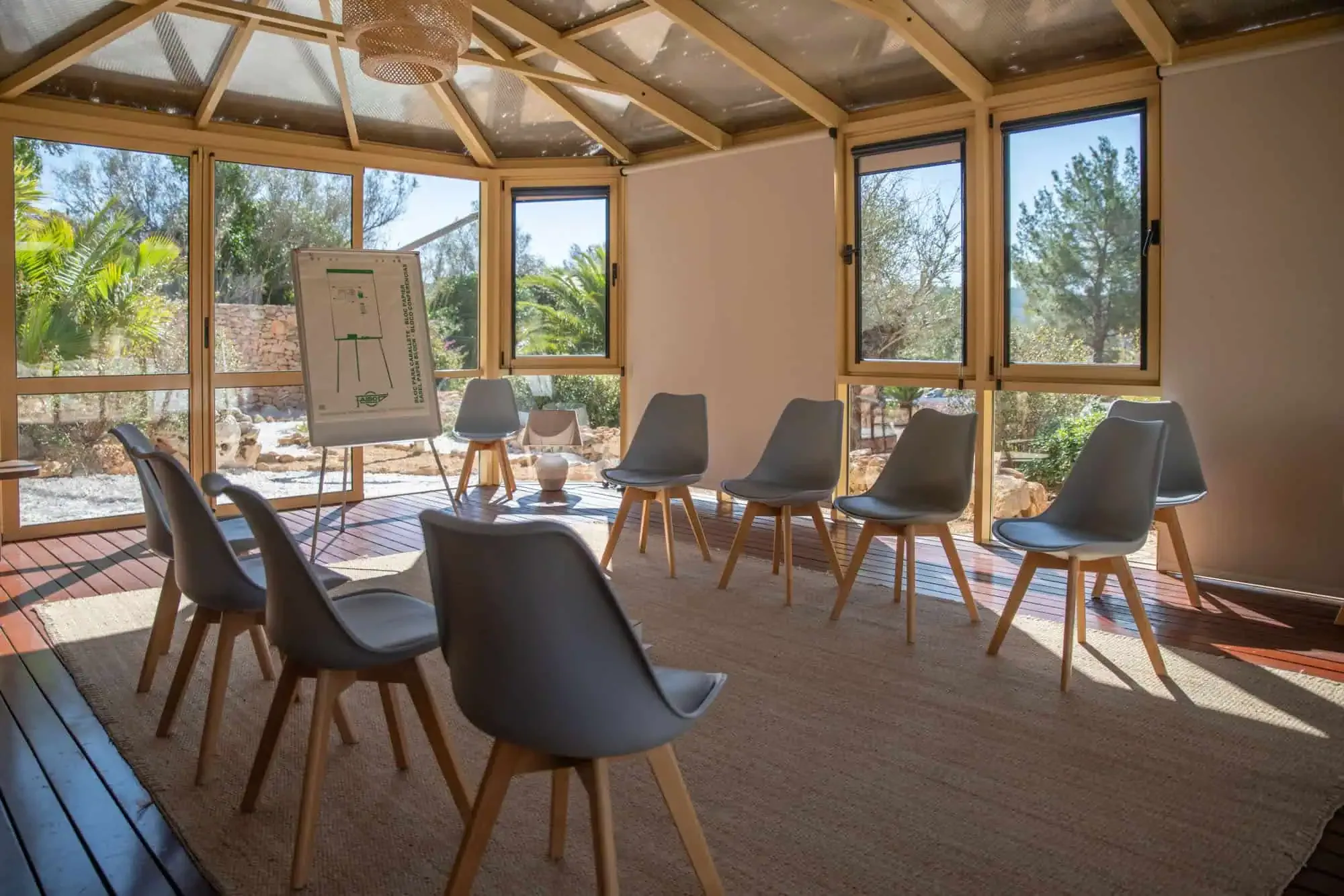 Group therapy room with a circle of grey chairs and a flip chart, glazed on two sides
