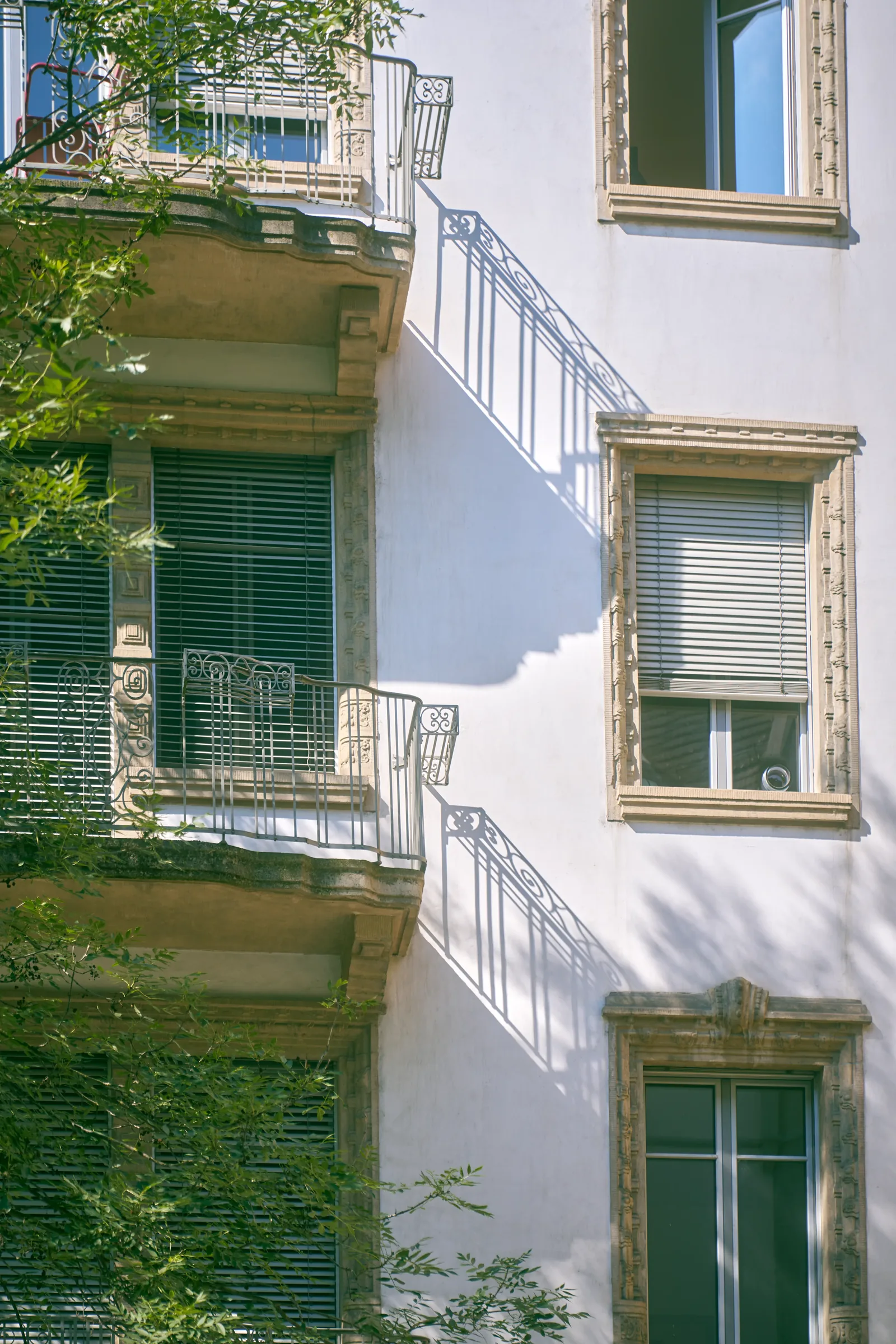 Pale facade of a historic Zurich residential building with stone window frames and iron balconies