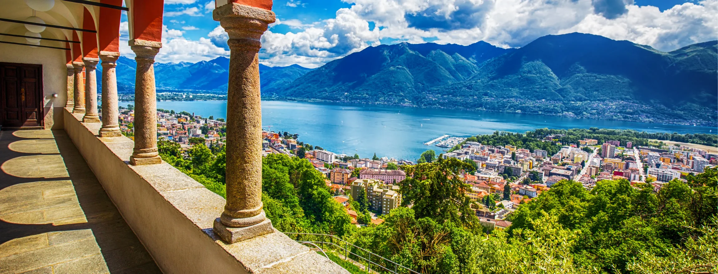 Stone column loggia overlooking green hills, Locarno and Lake Maggiore below mountains