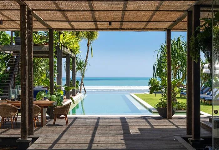 Timber pavilion with a deck opening onto an infinity pool and the ocean horizon at a Bali villa