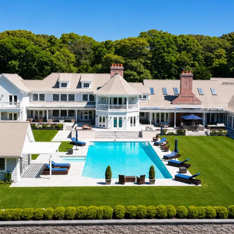 Elevated view of the main house facade with the pool, sun loungers and clipped hedges in spring