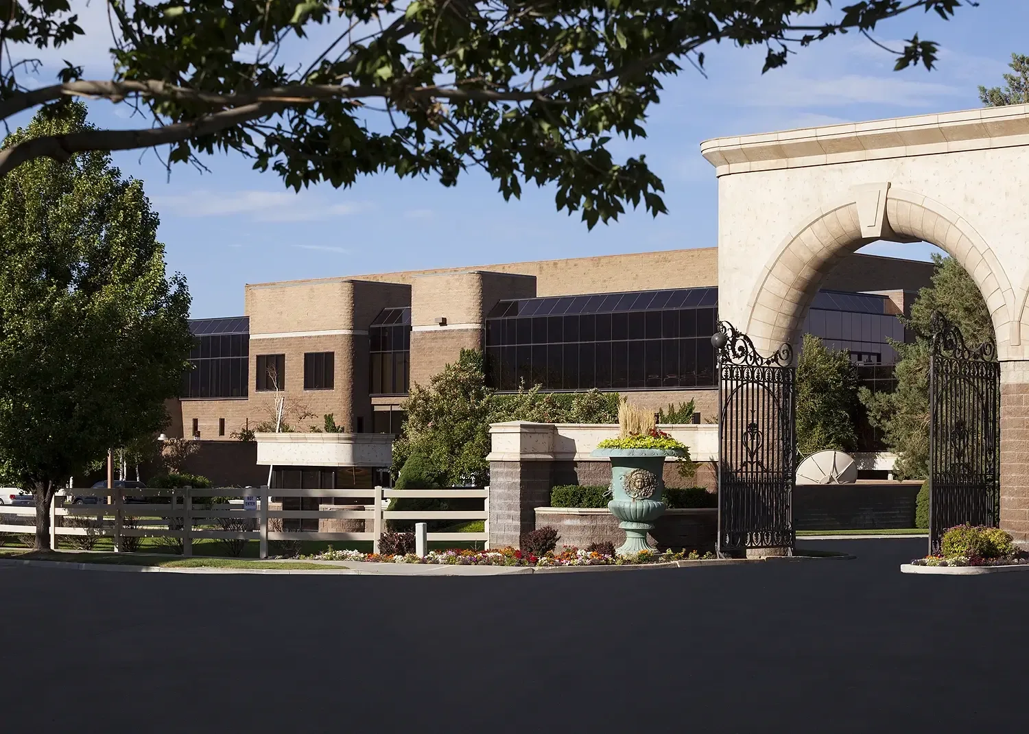 Stone archway with an iron gate in front of the low brick Studio building and landscaped driveway