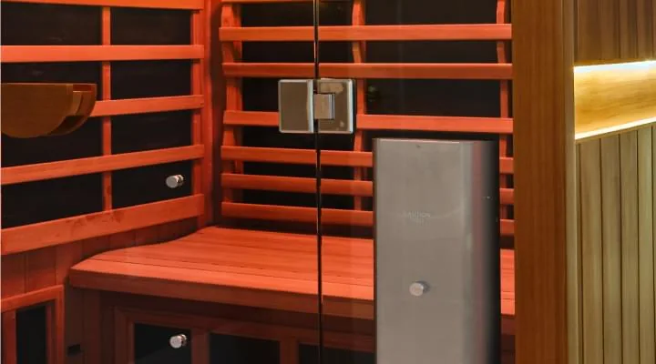 Wooden sauna cabin with slatted benches, warm side lighting and a glass door