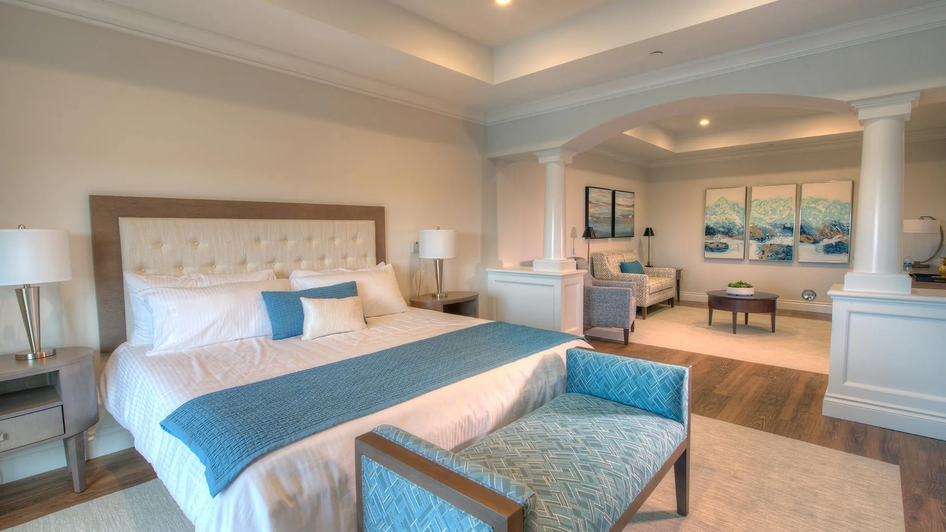 Suite bedroom with columned archway, blue curtains, a window view and a separate sitting area