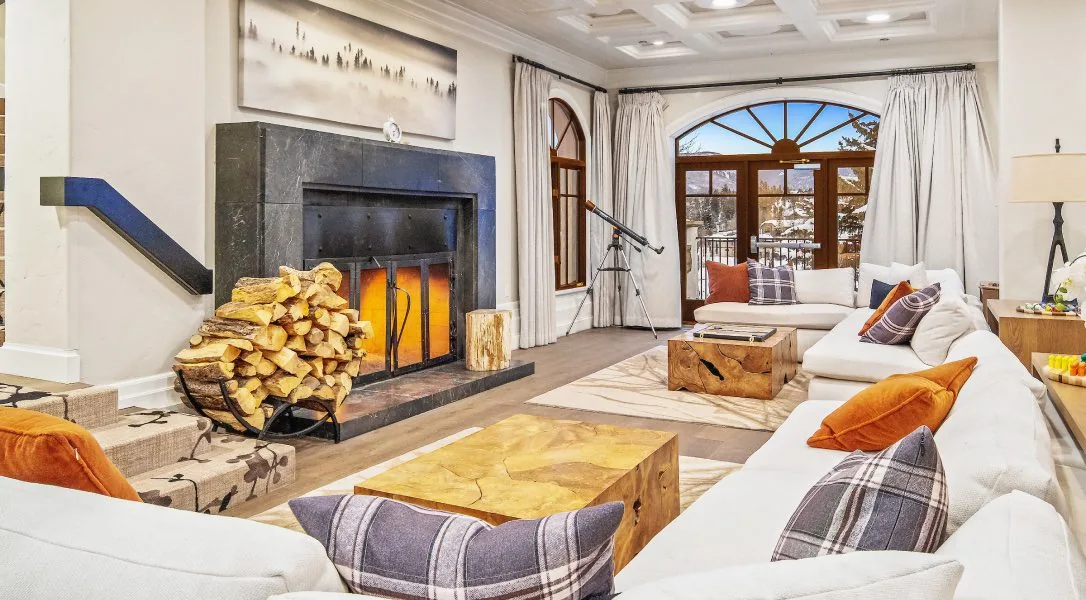 Lounge with white sofas, wooden coffee tables, a stacked log fireplace and arched windows