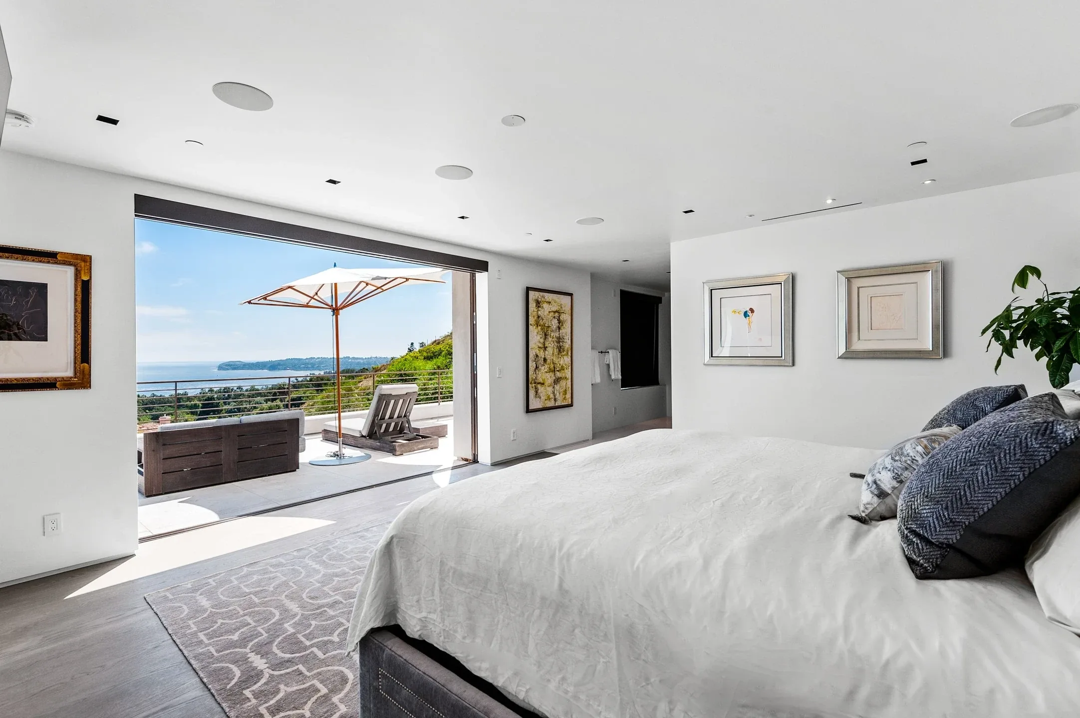 Bedroom with a large bed and sliding glass doors opening onto a terrace with a parasol and sea view