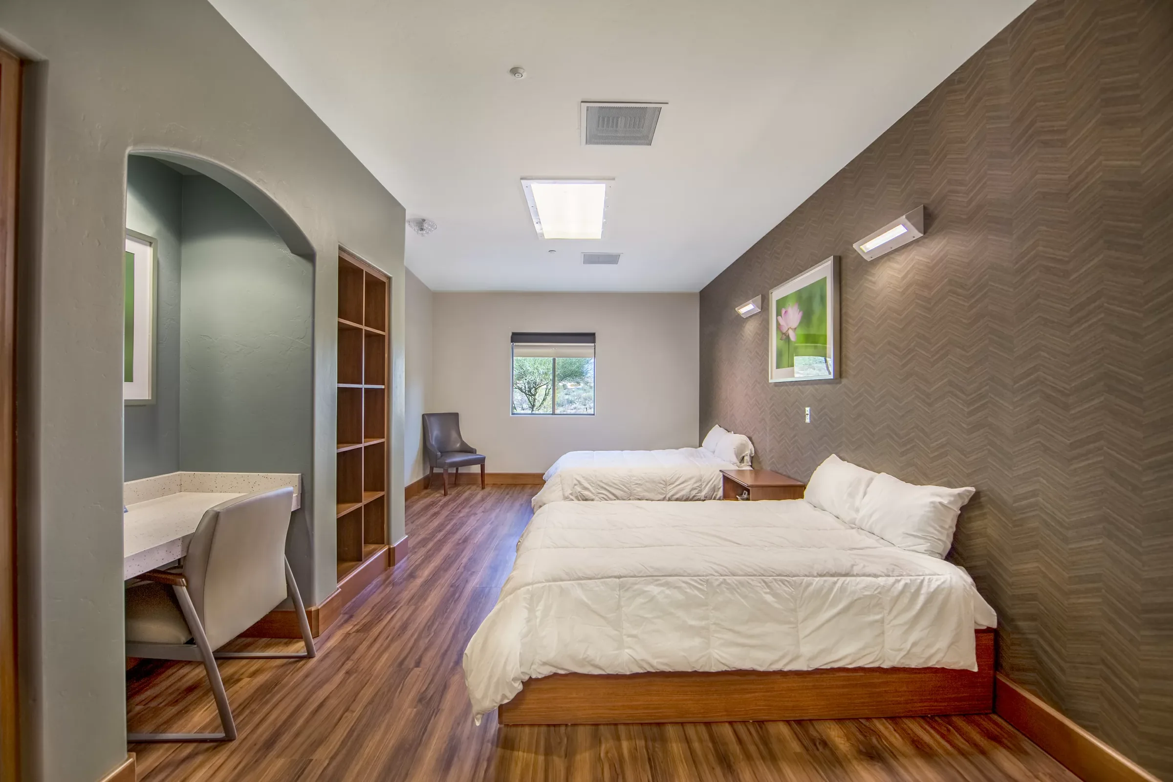 Residence bedroom with two single beds, wooden floor, desk and a framed print on a dark accent wall