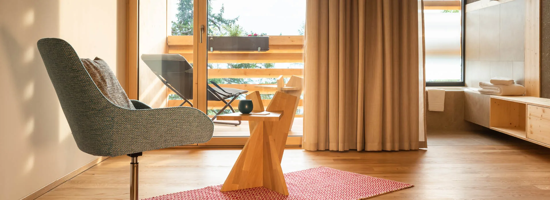Long dining room with small tables, a timber ceiling and a glass wall facing forest and mountains