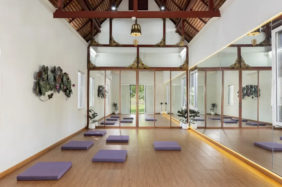Yoga studio with a timber vaulted ceiling, mirrored wall and purple mats laid out on a wooden floor